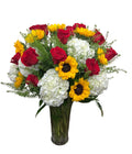 A beautifully arranged bouquet of red, yellow, and white flowers in a clear vase .